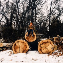 child on cut logs 