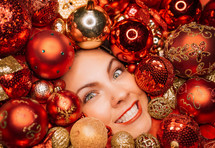 Young pretty woman face lights up with joy in Christmas tree toys balls. Wonder, happiness mood. Touch of magic. Holiday-themed projects, family-focused content or sentimental storytelling.