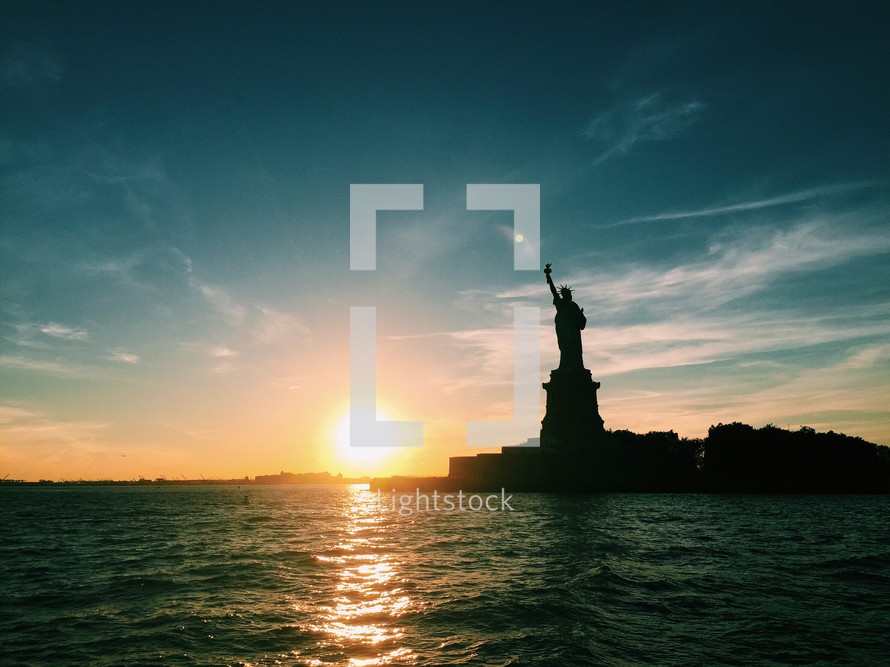 silhouette of the Statue of Liberty at sunset 