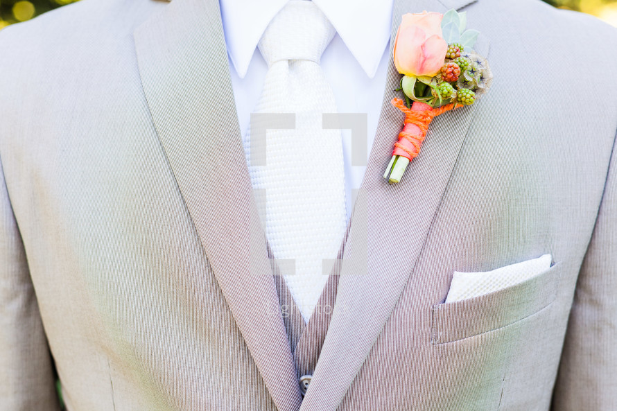 Chest of man in gray suit with orange boutonnière.
