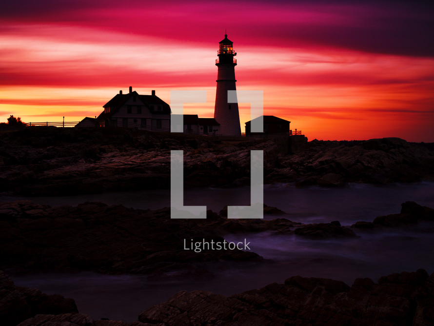lighthouse at sunset under a red sky 