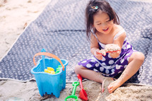 a little girl playing in the sand on a beach 