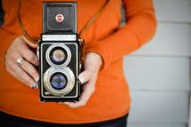A girl holds a vintage camera.