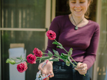 a woman cutting roses out of a garden 