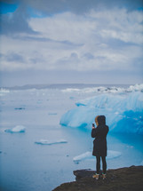 a woman taking pictures of icebergs 