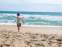 a boy running on a beach 