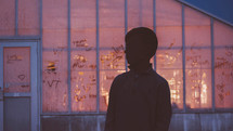 silhouette of a boy standing in front of an old warehouse building 