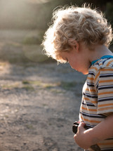 a blonde hair little boy playing outdoors 