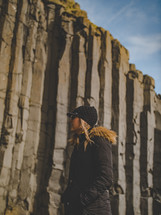 a woman walking in front of a rocky cliff 
