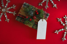 Merry Christmas Gift with blank name tag and Christmas snowflakes on a red background