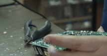 Worker inspecting and soldering electronic boards