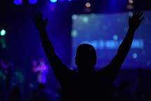 a man standing with raised hands and worship leaders leading a congregation in song 