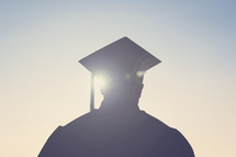 silhouette of a graduate standing outdoors 