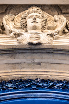 face in stone above an arched doorway in Paris 
