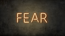 The word "fear" in neon letters on a grunge wall. 