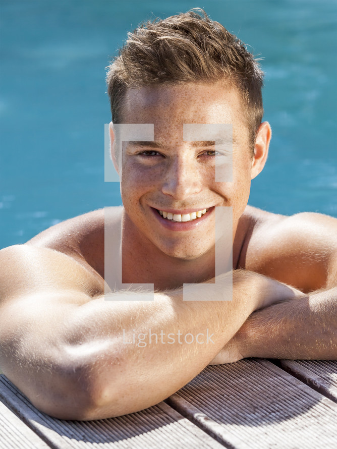 man smiling at the edge of a pool 