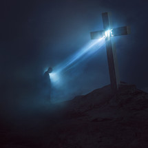 word love on a cross shining down on a man in darkness 