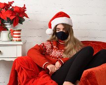 sad teenager wearing a mask and Santa hat 