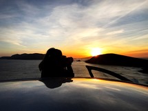 a photographer stepping out of her car to take a picture of the sunset.