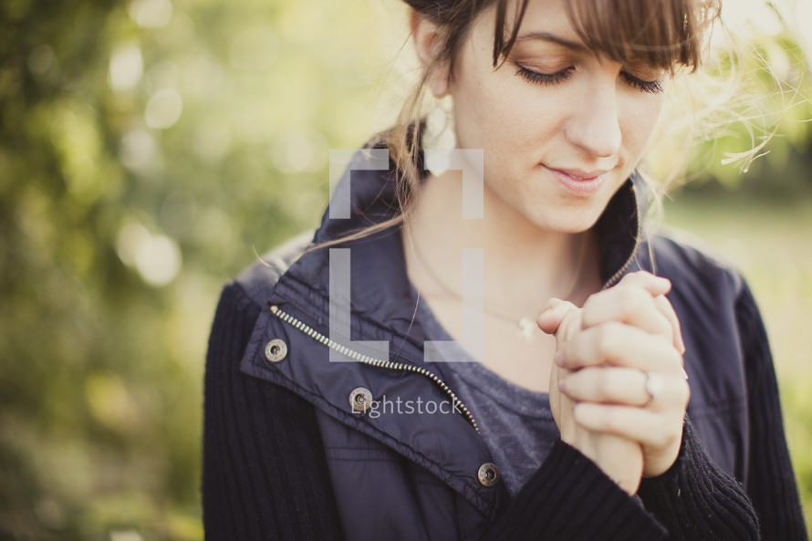 woman with her hands folded in prayer