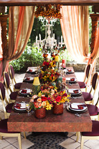 A table setting on a patio fall colors  chandelier 
