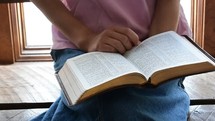 a girl sitting reading a Bible 