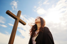 Young woman with a cross on the sky background