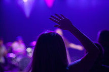 woman with a raised hand at a concert 