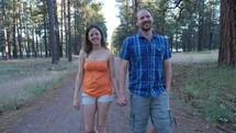 A happy young couple walking in a trail through the woods
