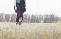 legs of a young woman standing in a field 