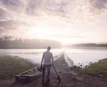 A man with a boat looks at a lake that has the waters parted