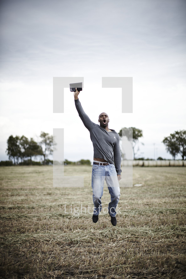 A man jumping in the air with a BIble in hand