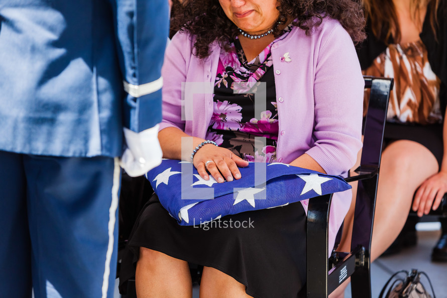 crying widow holding a folded American flag