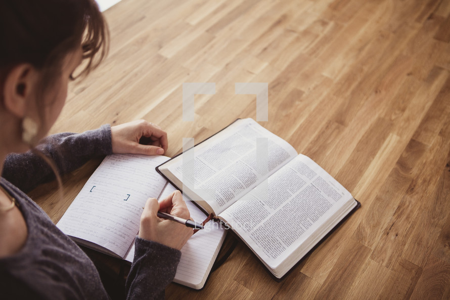 woman writing in a journal and reading a Bible