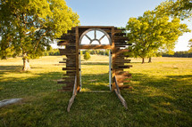 Window frame erected in the middle of a grassy green field with trees.