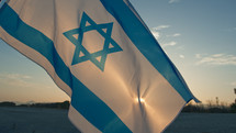 Israel flag Waving In the Sky on the beach at sunset