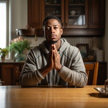A young man praying at home with his hands folded
