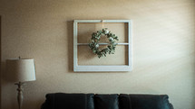eucalyptus wreath on an old window over a couch 