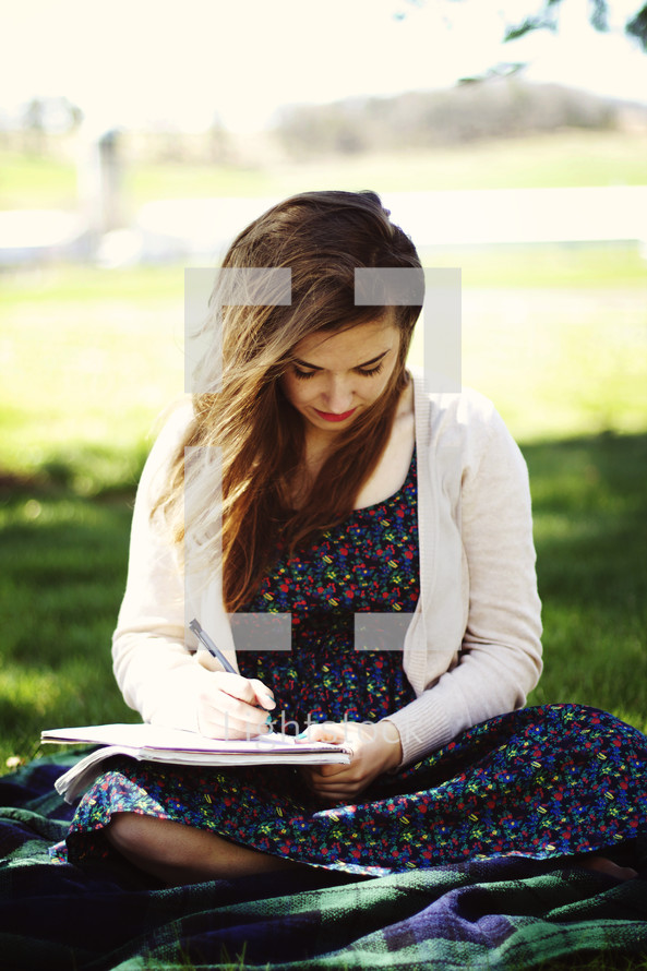 woman writing in a journal outdoors 
