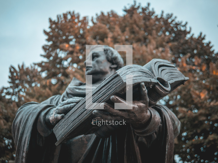 A statue of Martin Luther holding a bible in focus