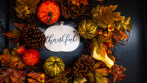 fall leaves, pumpkins, and pine cones with word thankful 