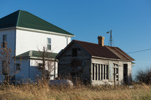 Old wooden house next to new white farm house