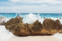 waves crashing into a rock on a beach 