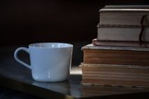 coffee cup and a stack of old books on a table 