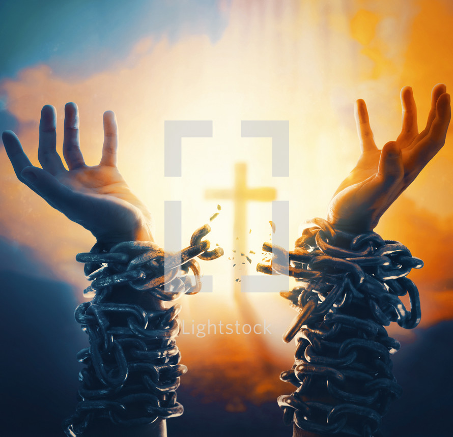 Two hands with broken chains and cross in the background.