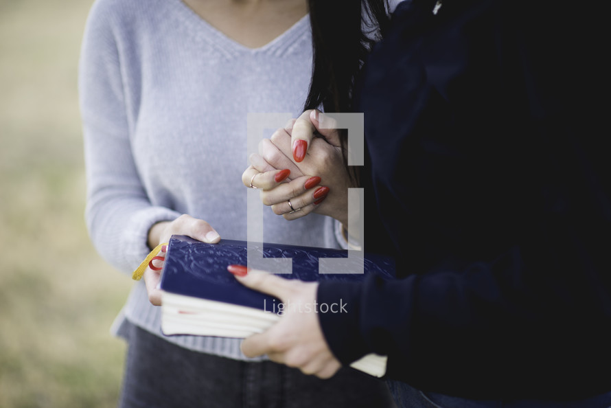 young woman holding a Bible and praying together 