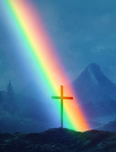 A beautiful rainbow lands near an old wooden cross