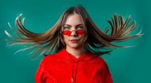 Portrait of woman with beautiful dancing hair on blue. Lady in red sunglasses with european appearance looking at camera. High quality photo
