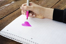 girl drawing a heart on paper 