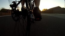 Low POV of a man riding his bike through a neighborhood at sunrise